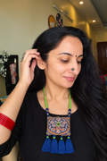 Woman wearing blue Kutchi fabric necklace with mirror work and tassels