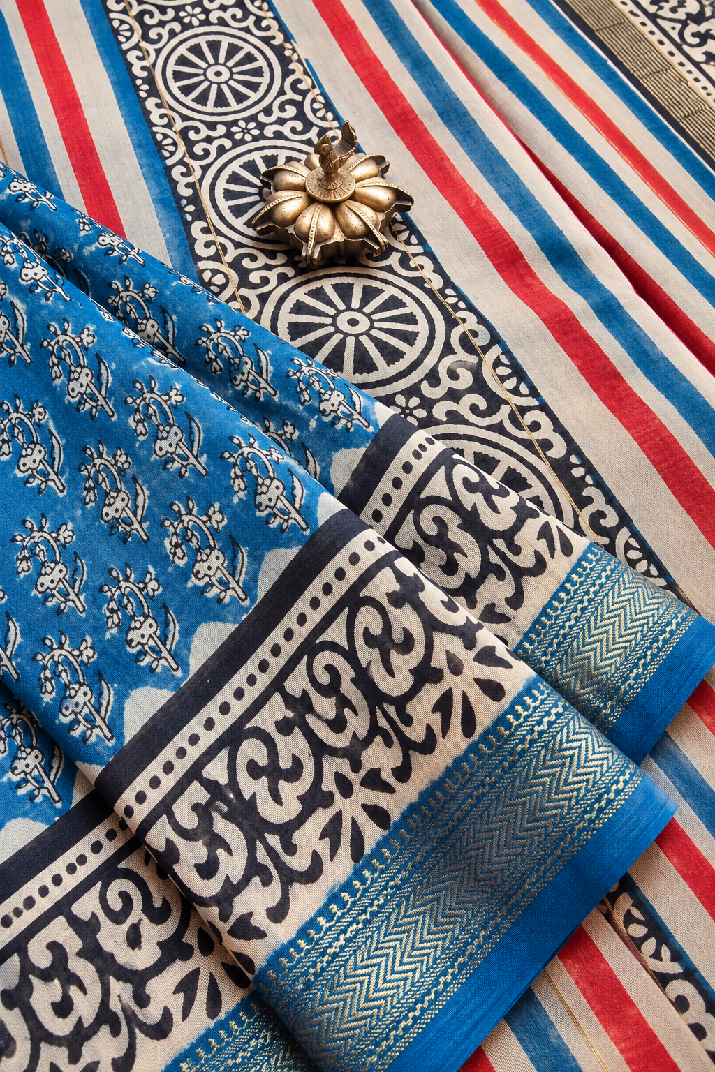 Shipra turquoise blue hand block printed silk cotton saree with floral motifs, red and blue striped pallu, traditional circular patterns and golden zari border by Tattva Crafted Elegance.